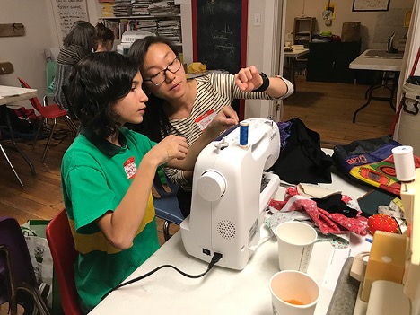 a woman showing a young person how to use a sewing machine