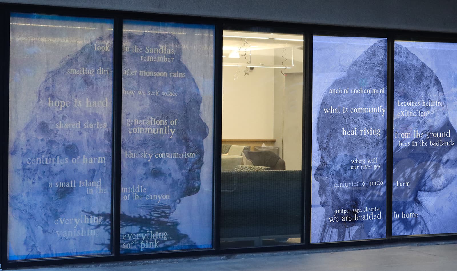photo of large scale paintings of head silhouettes that are predominantly blue with white words superimposed