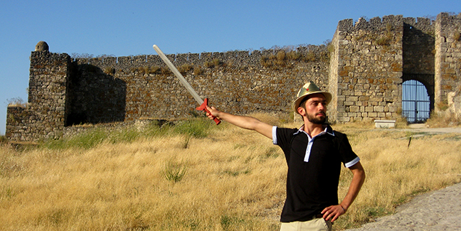 student posing with a fake sword in front of a castle
